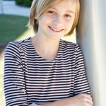 Sarah, celebrating her 12th birthday during our photo shoot, wears a tan and brown striped, three-quarter-sleeve dress from Blush.