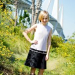 Sarah (12) poses with the Arthur Ravenel Bridge as a backdrop while wearing a sleeveless white and black knee length dress from Blush with knee high socks and black loafers. This outfit is perfect for adding or taking away layers throughout the fall.