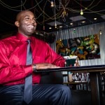 Jermaine looks smashing and ready for the holidays in this eye catching red, button down Van Heusen shirt and dark gray Madison tie provided by Belk in Mount Pleasant Towne Center. He enjoys a drink in the laid back atmosphere at Triangle Char & Bar.