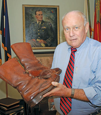 Pat Waters displays the boots his larger-than-life grandfather was wearing when he was involved in a fatal auto accident. In the background is a portrait of Waters’ father, also an Army general.