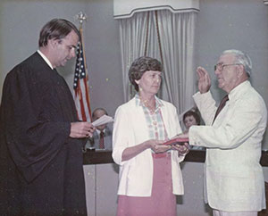 New Mayor Johnnie Dodds is sworn into office by Judge Thomas Lowndes. His wife, Flo Dodds, stands witness.