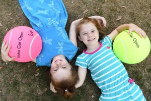 Young girls with large Volvo Car Open tennis balls