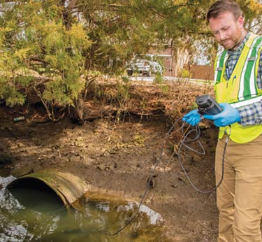 NPDES Coordinator Charlie Hansen uses a handheld meter to test the quality of water that eventually will end up in Shem Creek.