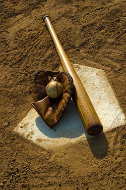 A Baseball, glove and bat laying on home plate