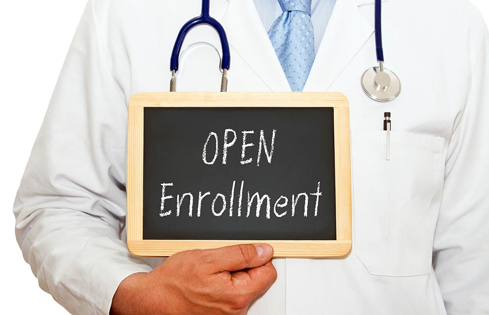 A man holding an 'open enrollment' sign