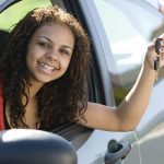 A teen smiles with car keys in her hand