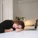 A young wo,an falls asleep at the dining room table while studying.