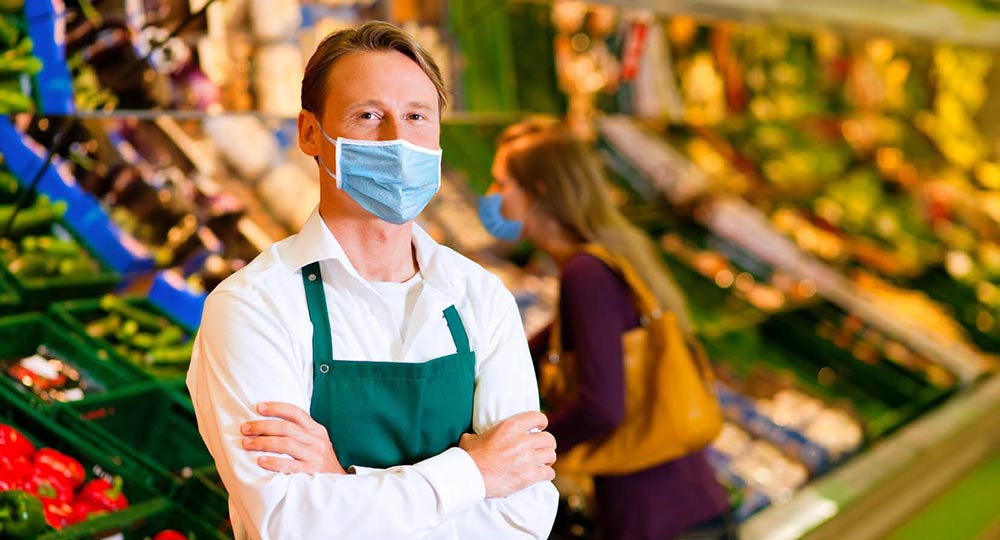 A grocery store employee with a shopper in the background