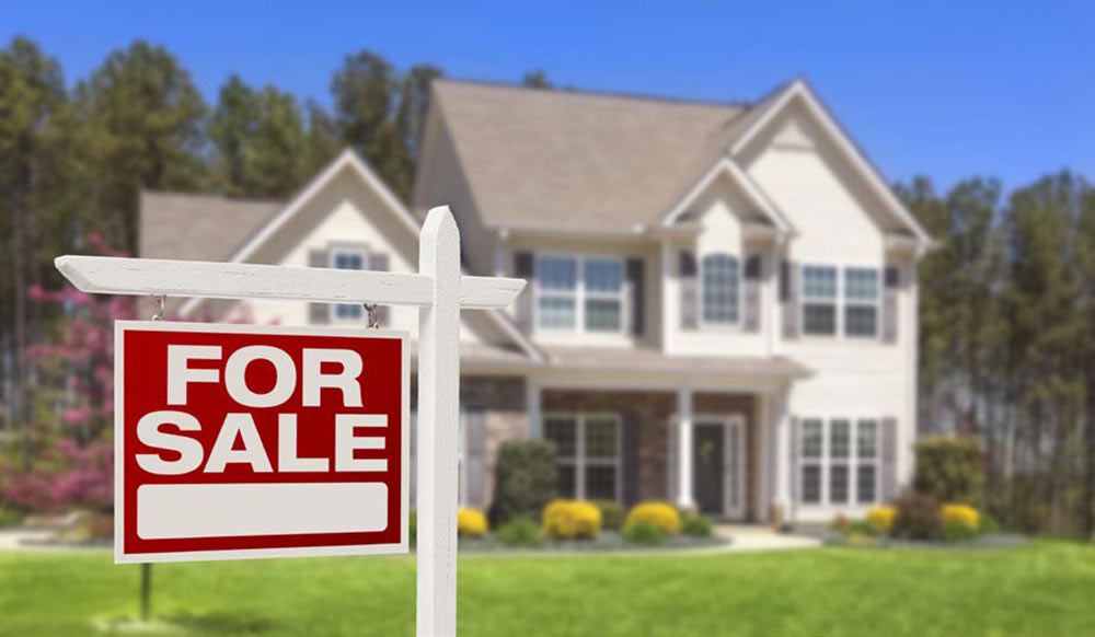 A house with a FOR SALE sign out front.