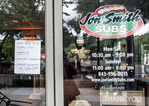 Jon Smith Subs. A hand-written sign reads.., 1130-7. We are still open for takeout -online ordering - FREE Delivery via Uber Eats