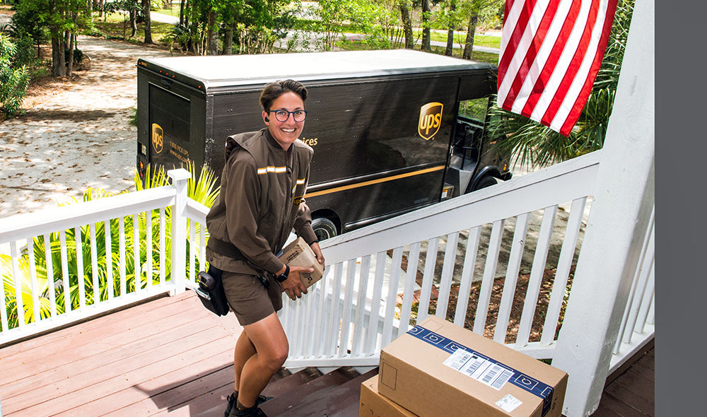 A UPS driver delivers packages to a customer's porch