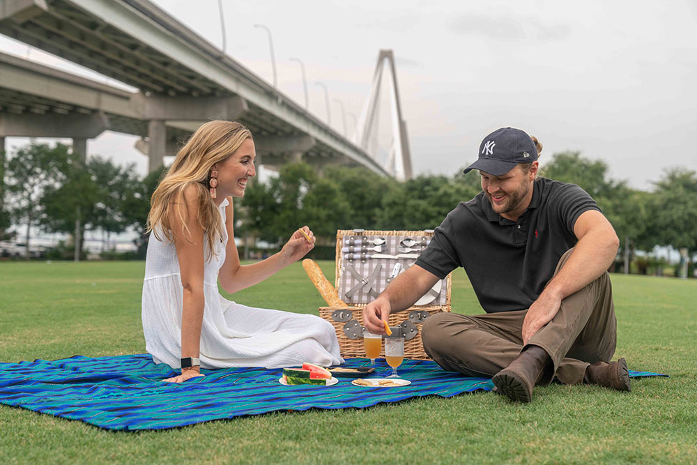 A couple enjoys a picninc with the Arthur Ravenel Bridge as a backdrop