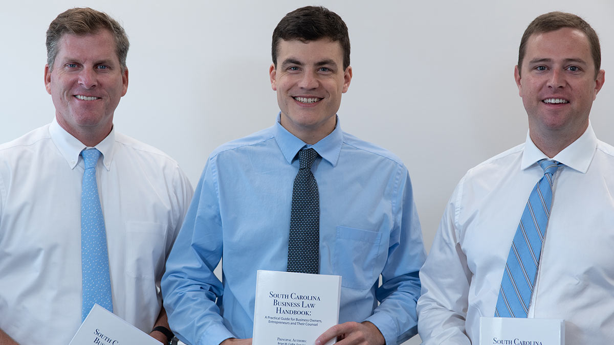 Jim Buxton, Nate Johnson and Brian Collie of Buxton & Collie Attorney at Law holding their South Carolina Bar publication, South Carolina Business Law Handbook: A Practical Guide for Business Owners, Entrepreneurs, and Their Counsel.