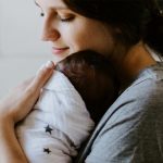 Mother and baby in a blanket. Photo by Kelly Sikkema on Unsplash.