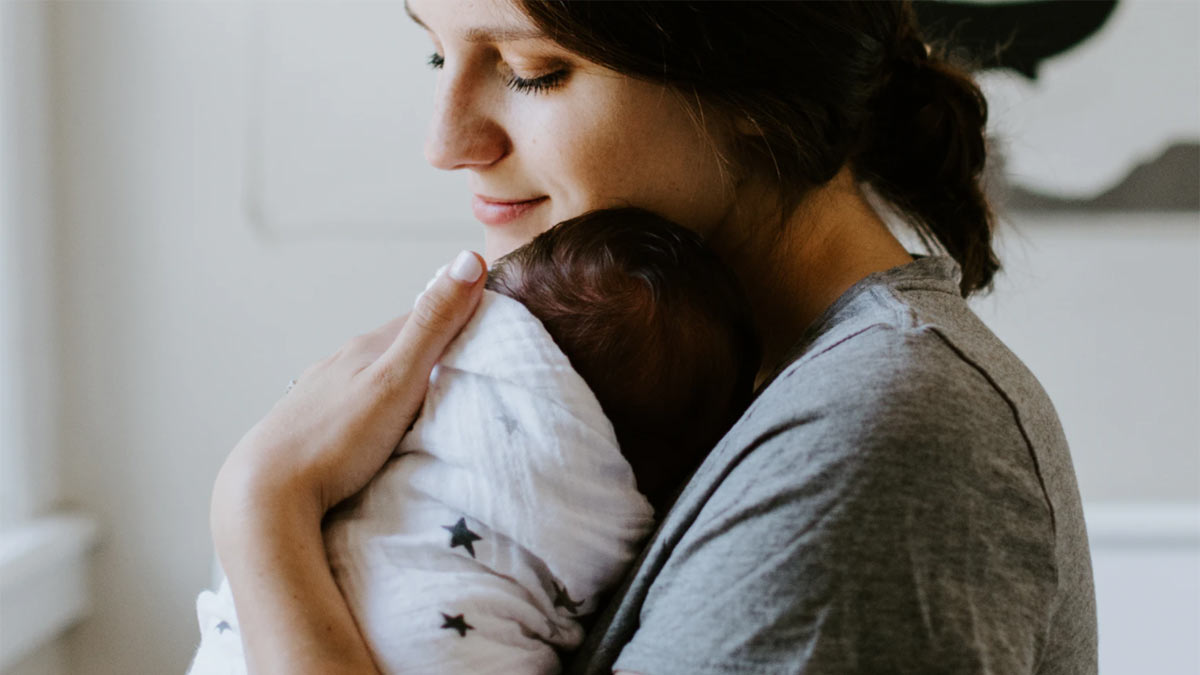 Mother and baby in a blanket. Photo by Kelly Sikkema on Unsplash.