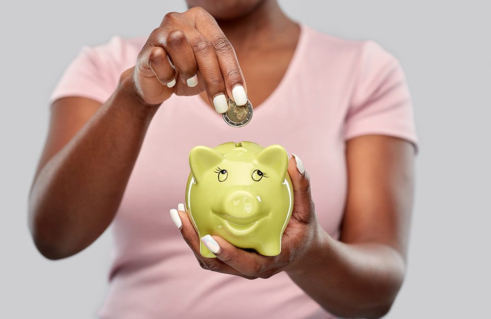 A woman puts a coin into her piggy bank for savings.