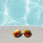 Photo of a swimming pool with sunglasses on the side. Photo by Pexels from Pixabay.