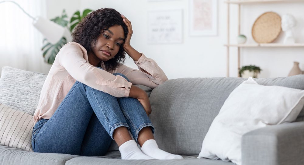 A depressed mother sitting on the couch.