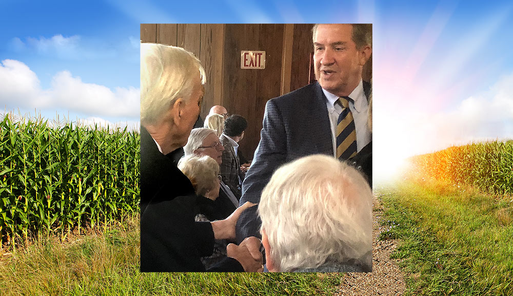 Commissioner Weathers shakes hands with Willie McRae set on background of a corn field.