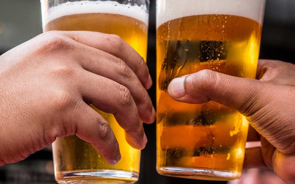 Oktoberfest photo, 2 hands raised with full beer glasses. Photo by Tembela Bohle from Pexels.