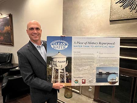 MP Waterworks GM Allan Clum poses with poster board illustrating the conversion of the former water tower to an artificial reef.