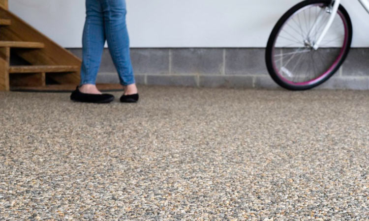 A woman and her bike on a stone and epoxy garage floor by Coastal Stone Flooring.