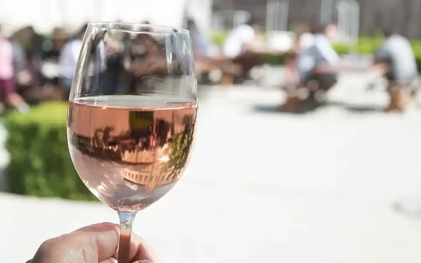 A woman holding a glass of rosé wine