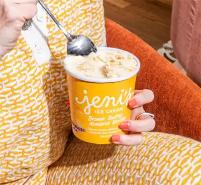 A woman taking a bite of Jeni’s Splendid Ice Creams' Brown Butter Almond Brittle ice cream