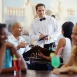 A waiter and restaurant patrons.