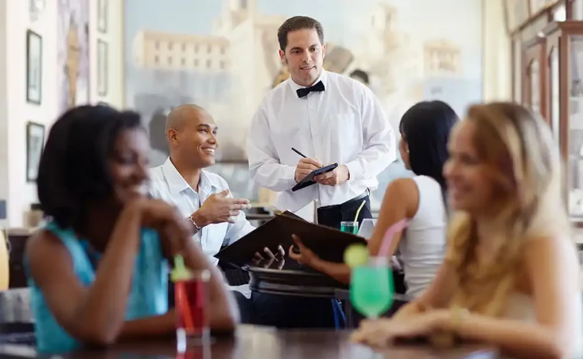 A waiter and restaurant patrons.