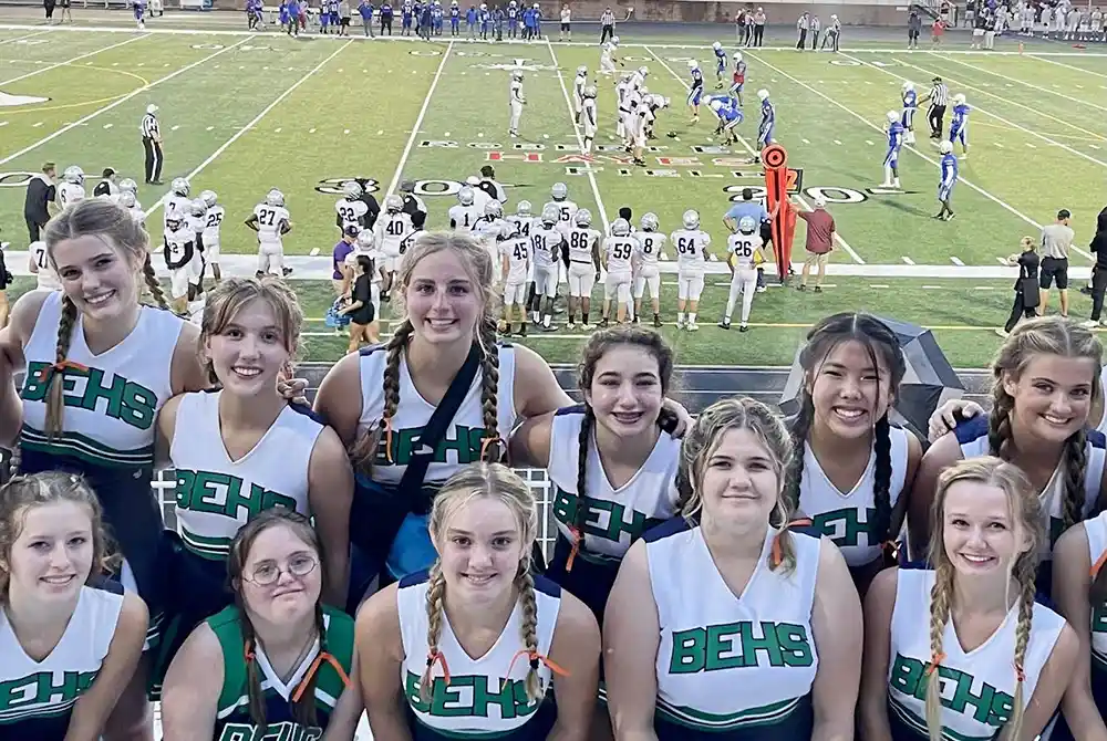 Cheerleaders with a football game in the background.