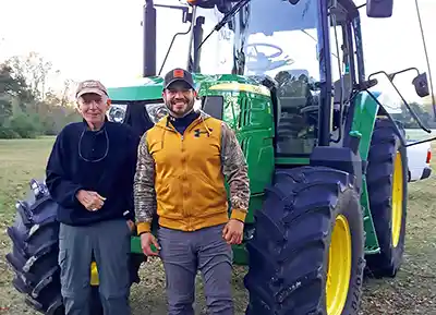 Willie McRae and Erik Hernandez in front of tractor.