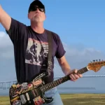 The Critic, Jim Voigt with guitar in hand, and the arthur Ravenel Bridge in the background