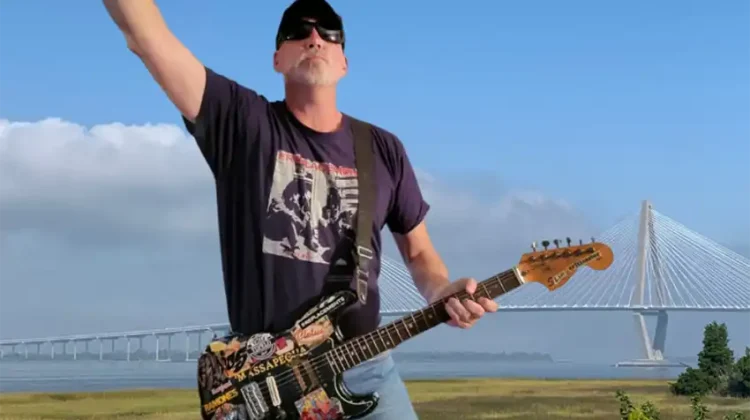 The Critic, Jim Voigt with guitar in hand, and the arthur Ravenel Bridge in the background