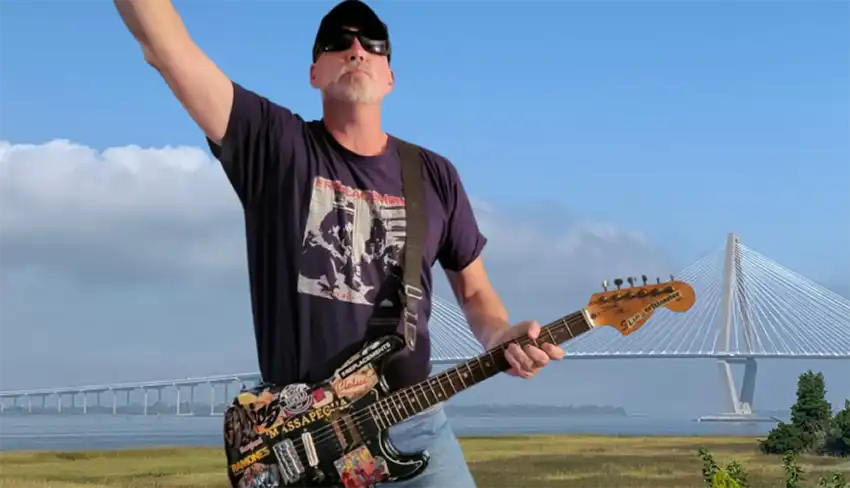 The Critic, Jim Voigt with guitar in hand, and the arthur Ravenel Bridge in the background