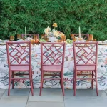 A beautiful meal setup with scenic greenery by the table, which is set with dishes, fine tableware, candles and a floral centerpiece - by Curated Events.