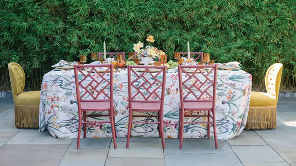 A beautiful meal setup with scenic greenery by the table, which is set with dishes, fine tableware, candles and a floral centerpiece - by Curated Events.