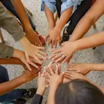 A group of people join hands together to help others. Photo credit Shelby Murphy Figueroa on Unsplash.com.