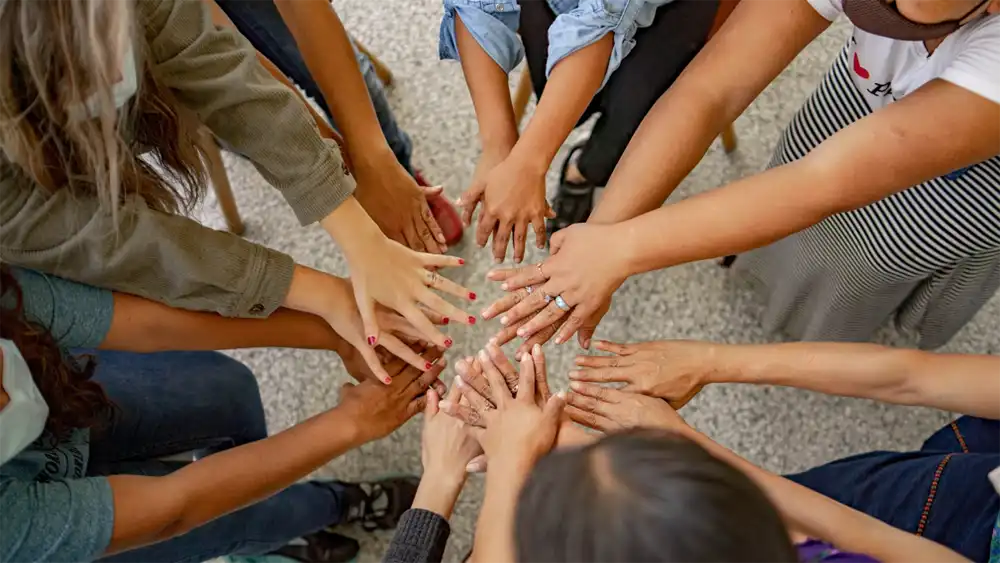 A group of people join hands together to help others. Photo credit Shelby Murphy Figueroa on Unsplash.com.