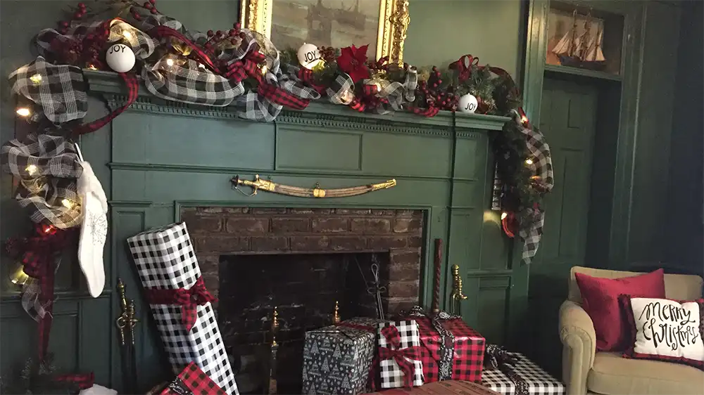 A fireplace, mantle, living room couch decorated for the holiday 