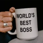 A woman holidng a World's Best Boss coffee mug. (Edited) photo by Kelly Sikkema on Unsplash.