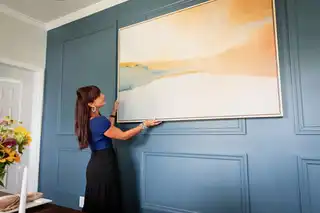 A woman hanging a painting.