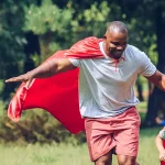 Superhero dad with his superhero son running in their yard.