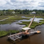 Photo of the home in the distance taken from the marsh showing the private deep-water dock with lift and floating dock.