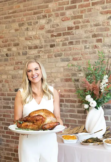 Candice Hudnall, President + Owner of Hamby Catering and Events holds a beautiful prepared turkey on .a platter. Photo by Aleece Sophia Photography.