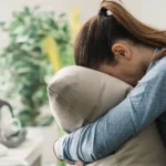 A depressed woman crying into a pillow