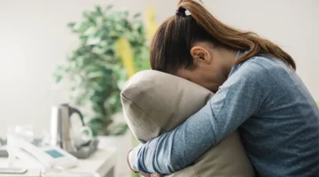 A depressed woman crying into a pillow