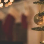 Holiday photo showing a Christmas Tree with stockings hung in the background by Chad Madden on Unsplash.com