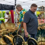 An outdoor festival booth filled with dozens of detailed, hand-woven sweetgrass baskets on display at the Mount Pleasant Sweetgrass Festival.