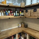 A meticulously organized walk-in pantry featuring clean butcher block counters and labeled storage baskets. Photo provided by SHIFT into Organized.